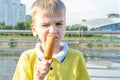 Hungry kid eating street food on the beach in summer. A little emotional boy eating fried sausages on a stick