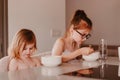 Hungry kids sitting at table in kitchen and eating fresh cooked meal from white plates. Tasty lunch at cozy home