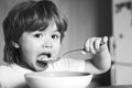 Hungry little boy eating. Cheerful baby child eats food itself with spoon. Tasty kids breakfast. Baby eating food on Royalty Free Stock Photo