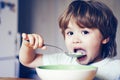 Hungry little boy eating. Cheerful baby child eats food itself with spoon. Tasty kids breakfast. Baby eating food on Royalty Free Stock Photo