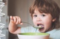 Hungry little boy eating. Cheerful baby child eats food itself with spoon. Tasty kids breakfast. Baby eating food on Royalty Free Stock Photo