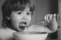 Hungry little boy eating. Cheerful baby child eats food itself with spoon. Tasty kids breakfast. Baby eating food on Royalty Free Stock Photo