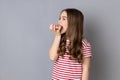 Hungry little girl standing biting doughnut and enjoying sweet sugary confectionary.