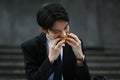 Hungry male office worker in formal wear sitting on stairs outside office and eating tasty sandwiches during lunch