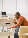 Hungry man eating a sandwich and typing on laptop Royalty Free Stock Photo