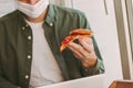 Hungry man freelancer eat italian pizza while working on laptop at home