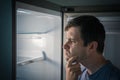 Hungry man is looking for food in empty fridge at night Royalty Free Stock Photo