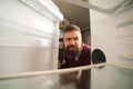 Hungry man looking for food in empty fridge. Man panics during coronavirus quarantine. Bearded man looking into empty fridge. Royalty Free Stock Photo