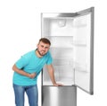 Hungry man near empty refrigerator on white background Royalty Free Stock Photo