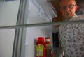 Hungry man opening and looking for food in refrigerator, at the empty refrigerator. Senior man looking for a snack in Royalty Free Stock Photo