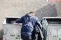 Hungry Man rummaging in trash container bin. Homeless boy searching for food in garbage. Poor and desperate person digging dumpste