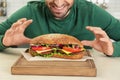 Hungry man and tasty sandwich on table Royalty Free Stock Photo