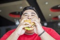 Hungry obese man eating a big burger
