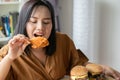 Hungry overweight woman holding Fried Chicken, hamburger on a wooden plate and Pizza on table, During work from home, gain weight