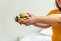 Hungry overweight woman smiling and holding hamburger and sitting in the bedroom, her very happy and enjoy to eat fast food.