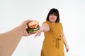 Hungry overweight young Asian woman holding hamburger on isolated background, Her hungry all time and overeat, gluttony and binge