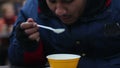 Hungry pauper eating food donated by volunteers, charity event for poor people