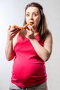 Hungry pregnant woman with a large slice of pizza