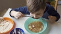 Hungry preschool boy eating soup from a green bowl. Charming Caucasian child eats himself. High angle view