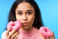Hungry pretty girl eating donuts isolated over blue background