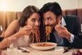 Hungry, restaurant and couple eating spaghetti for love, crazy fun and sharing plate on valentines date celebration Royalty Free Stock Photo