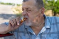 Senior driver eating patty filled with fried cabbage near his car on a summer road Royalty Free Stock Photo