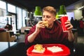 Hungry student bites a burger and holds a drink in front of a fast-food restaurant