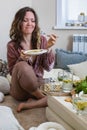 Hungry woman eating pasta spaghetti at serving table with wrapped gift box enjoy holiday celebrating