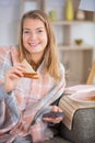 hungry woman holding sandwich while watching tv