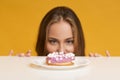 Hungry woman looking at donut with appetite, peeking out of table