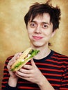 The hungry young man eats a hamburger