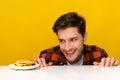 Hungry Young Man Looking At Burger Peeping Out Table