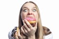 Hungry young woman with appetite eats a donut with pink icing and colorful topping. Popular fast food, junk food and diets. Close-