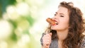 Hungry young woman eating meat on fork over green