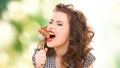 Hungry young woman eating meat on fork over green