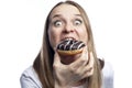 Hungry young woman in a white t-shirt eats a donut with chocolate icing. Unhealthy fast delicious food. Isolated on white