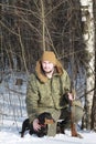 Hunter with black dachshund and shotgun in winter forest