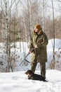Hunter with black dachshund and shotgun in winter forest