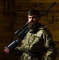 Hunter, brutal hipster on strict face with gun ready for hunting. Gamekeeper concept. Man with beard wears camouflage