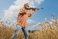 Hunter in cap and sunglasses aiming a gun at field Royalty Free Stock Photo