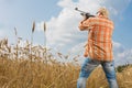Hunter in cap and sunglasses aiming a gun at field Royalty Free Stock Photo