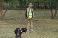 A hunter with a gun in his hands in hunting clothes in the autumn forest in search of a trophy. Royalty Free Stock Photo