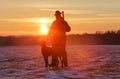 A hunter in a hat with a gun and a German shorthair pointer dog breed stands on a meadow covered with snow. Majestic winter. Royalty Free Stock Photo