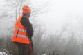 Hunter with high visibility clothing and rifle, waiting for boar hunting in foggy countryside. Hunt concept Royalty Free Stock Photo