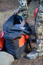 Hunter man wearing camo, digs through a bag for gear, while on a hunting trip