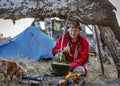 Hunter prepares dinner on a fire under broken tree Royalty Free Stock Photo