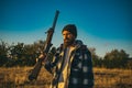 Hunter with shotgun gun on hunt. Bearded hunter man holding gun and walking in forest.