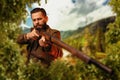 Hunter sitting in the bushes and aiming a rifle. Royalty Free Stock Photo
