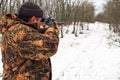 Hunter with a sniper rifle in the winter forest. A man is looking for a target Royalty Free Stock Photo