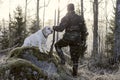 Hunter watching the sunrise in the morning in Finland. He has a shotgun in his hand and wearing a camouflage uniform.